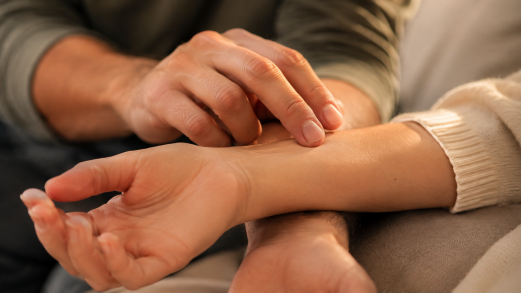 A close-up of fingertips tracing slowly along the inside of a partner's forearm and wrist